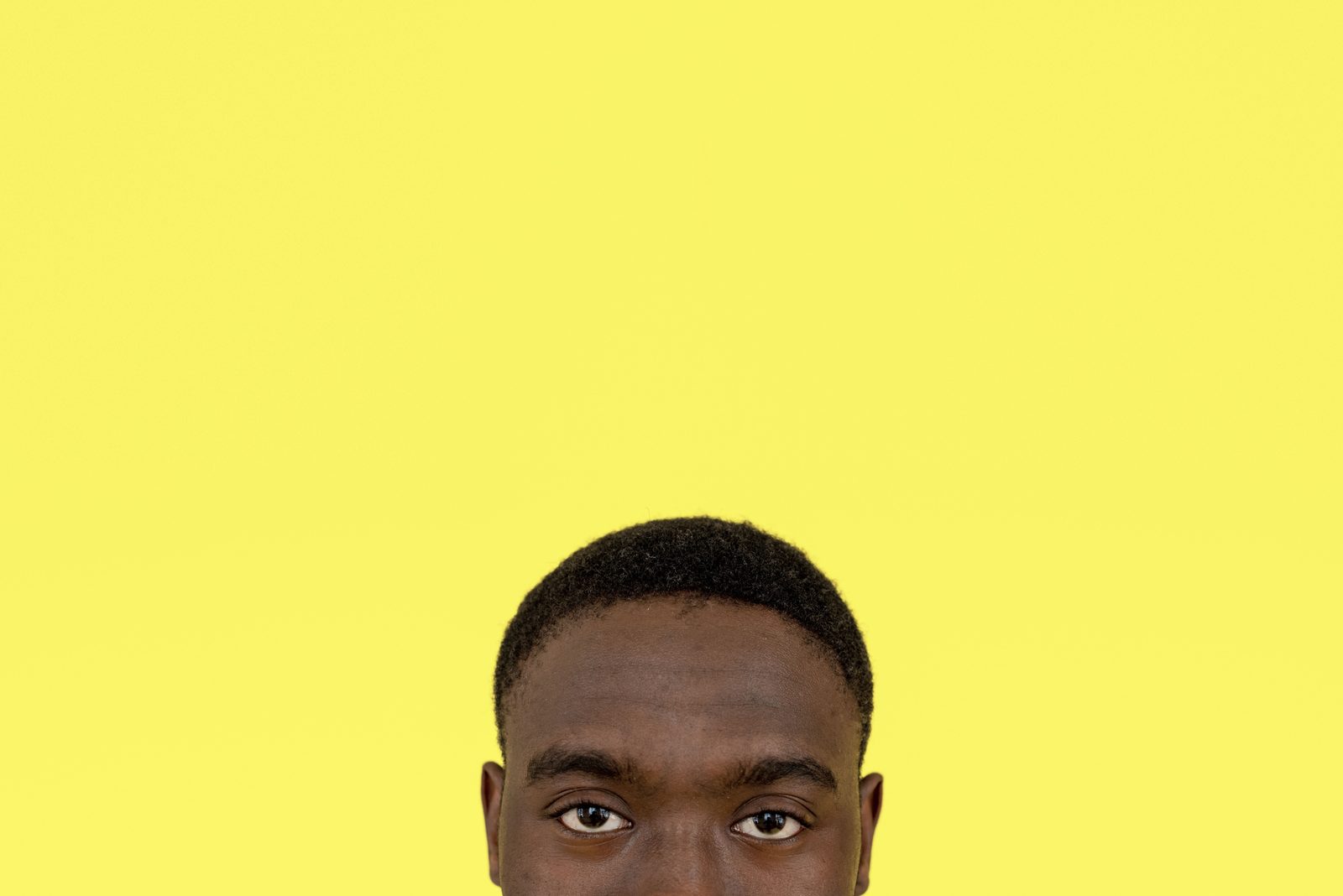 The top of a man's head and his eyes at the bottom of a yellow background.