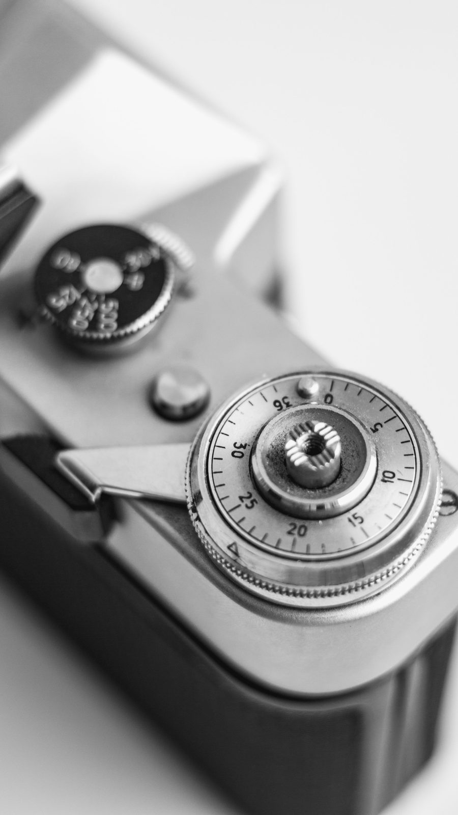 A close-up of the shutter speed dial on a black and silver film camera.
